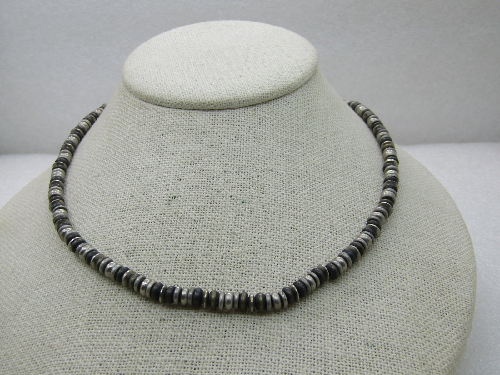 Vintage 5mm Silver Tone DIsc Beaded Necklace, Signed AE, 17" (American Eagle Brand). Shades of: Title: Vintage 5mm Silver Tone DIsc Beaded Necklace, Signed AE, 17" (American Eagle Brand). Shades of silver tone and brass tone beads -like a metal puka shell necklace with lobster clasp. Good to