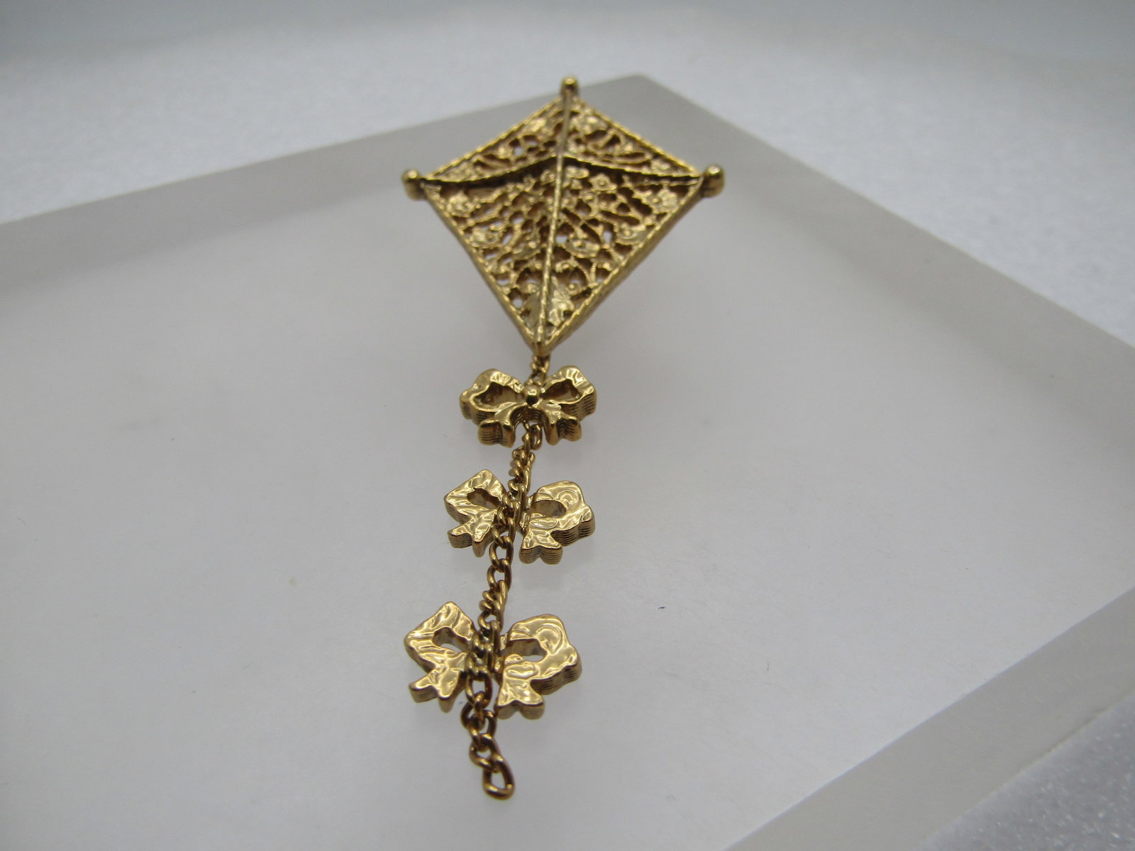 Vintage Filigree Kite Brooch, With Tail by 1928, 1980's: Title: Vintage Filigree Kite Brooch, With Tail by 1928, 1980's Description: Vintage Filigree Kite Brooch, With Tail by 1928, 1980's. The brooch has three bows on a chain tail with a filigree kite