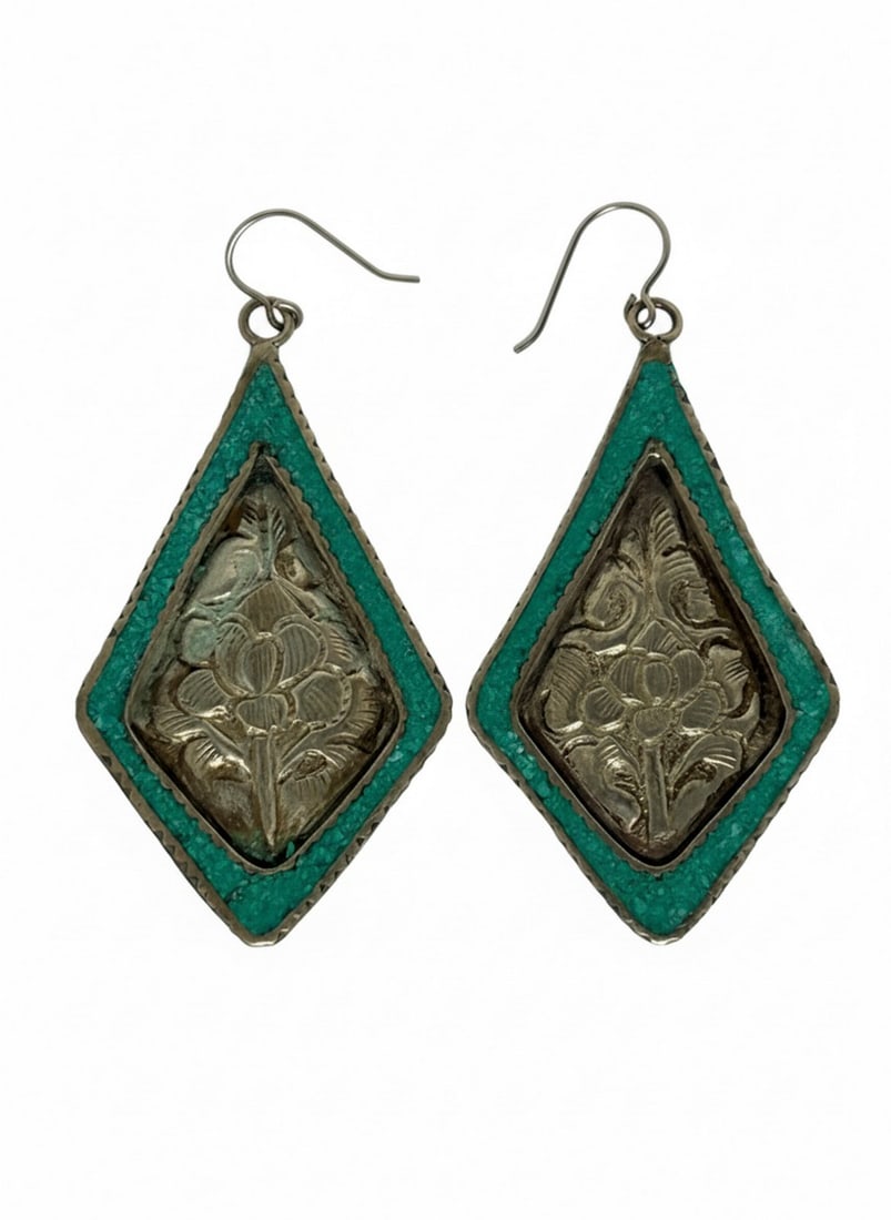 Sterling Silver and Turquoise Inlay Floral Motif Dangle Earrings: These striking dangle earrings feature a diamond-shaped design with an ornate floral motif intricately carved into sterling silver. The silverwork is bordered by a vibrant turquoise inlay, adding a