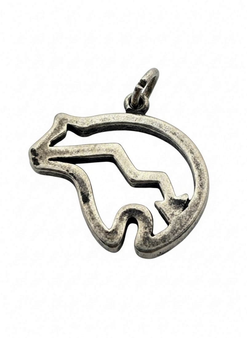 Sterling Silver Bear Fetish Pendant: A sterling silver pendant depicting a stylized bear fetish, featuring a cutout design representing the bear's heartline. This piece is likely inspired by Native American Zuni or Southwest art.
