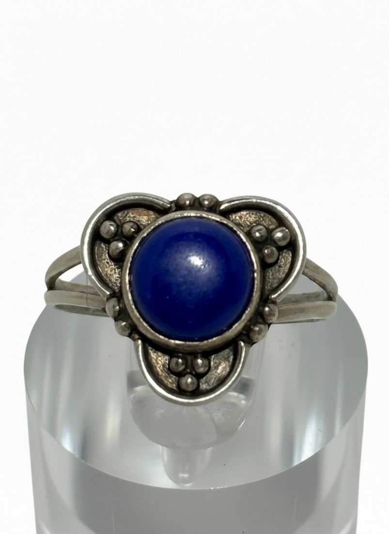 Sterling Silver and Lapis Lazuli Ring: This ring features a vibrant blue lapis lazuli cabochon stone set in sterling silver. The setting has an ornate, possibly floral-inspired design with small silver bead accents surrounding the central