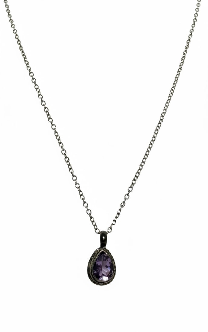 Sterling Silver and Amethyst Teardrop Pendant Necklace: A sterling silver cable chain necklace featuring a teardrop-shaped pendant with a faceted amethyst stone. The pendant has a decorative border with milgrain detailing. The metal appears to have an anti