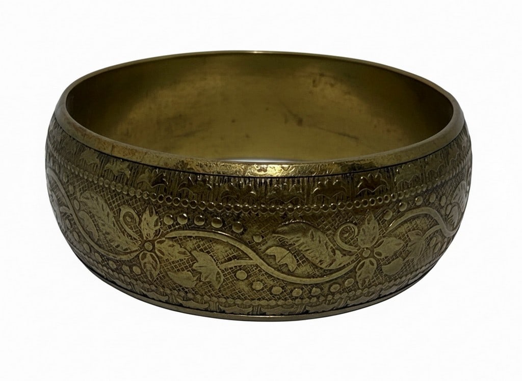 Antique Brass Bangle Bracelet with Engraved Floral Motifs: This antique brass bangle bracelet features intricate engraved floral and vine patterns across its surface, complemented by textured detailing. The bracelet has a solid, continuous form, suggesting