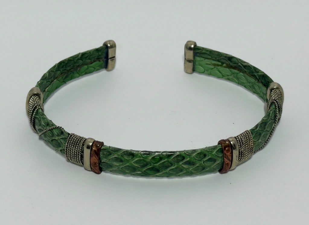 Green Snakeskin and Mixed Metal Cuff Bracelet: Fashionable cuff bracelet featuring a green snakeskin-patterned band accented with sections of coiled wire in silver-tone and copper-tone metals. The ends of the cuff are capped with silver-tone