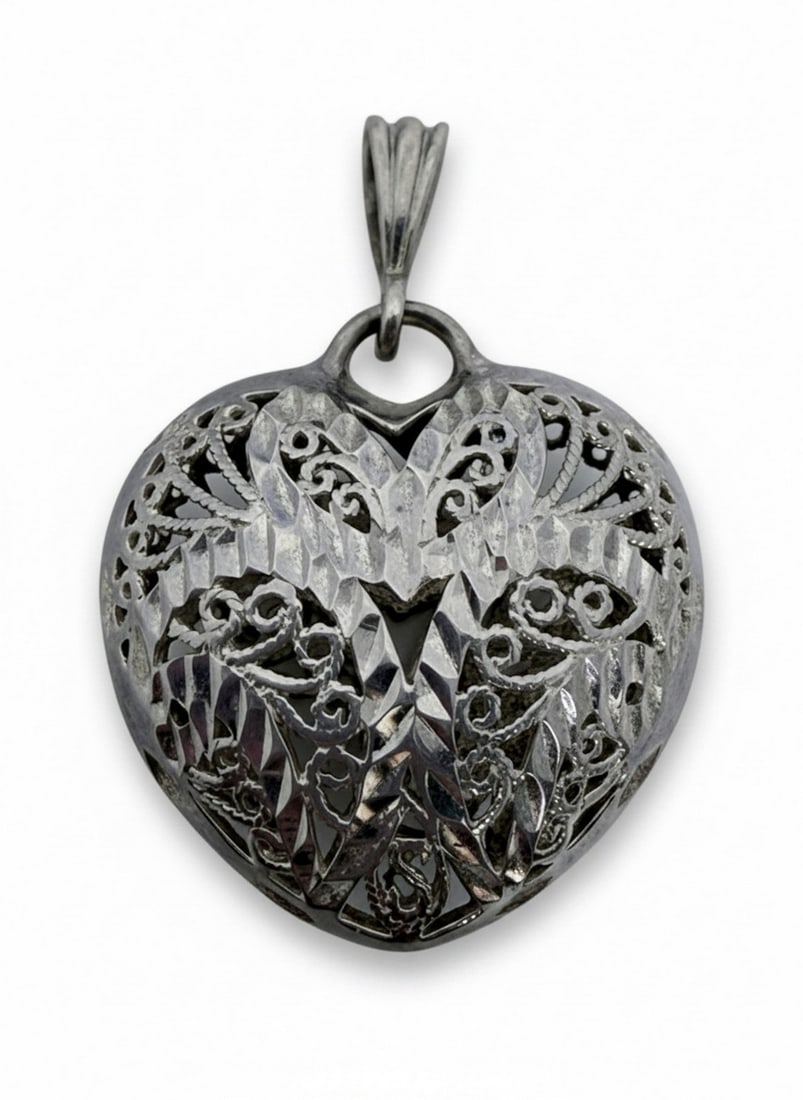 Sterling Silver Filigree Heart Pendant: A delicate sterling silver heart-shaped pendant featuring intricate filigree work and faceted detailing. The design incorporates elegant scrolls and cut-outs, creating a lacy, openwork appearance.