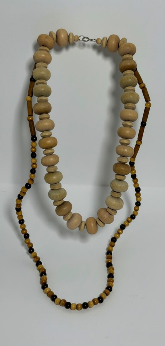 Lot of Two Beaded Wood Necklaces: This lot features two distinct beaded wood necklaces. One necklace consists of larger, roundish light wood beads of varying sizes, strung together without spacers. The second necklace is longer and