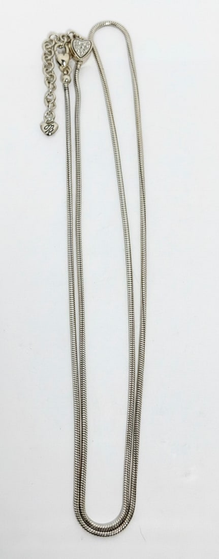Brighton Silver Tone Crystal Heart Slider Pendant Necklace: A contemporary Brighton silver-tone necklace featuring a slider pendant in the shape of a heart, adorned with clear crystals. The necklace has a snake chain design that can be adjusted in length.