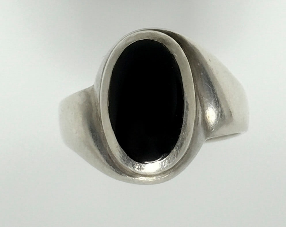 Sterling Silver and Black Onyx Cabochon Ring: A sleek and substantial sterling silver ring featuring a central oval black onyx cabochon, bezel-set. The band is smooth and polished. Jewelry Type: Ring Metal: Sterling Silver Hallmarks: 925 Primary