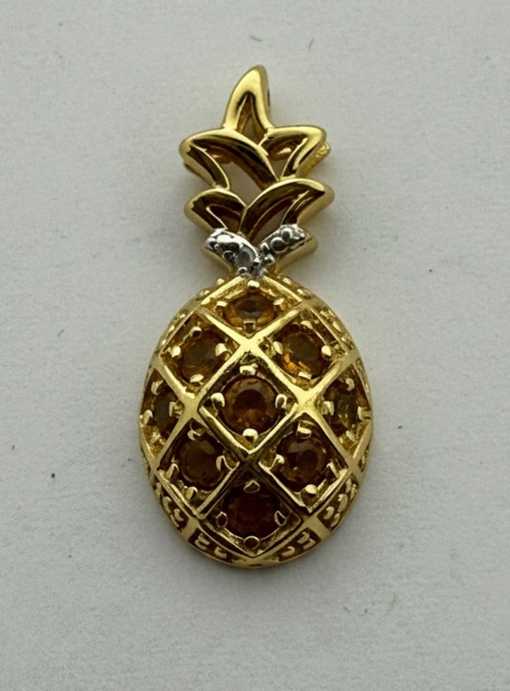 14K Gold and Citrine Pineapple Pendant: A whimsical pineapple pendant crafted from 14K yellow gold, featuring a lattice design set with numerous round-cut citrine gemstones in a warmer yellow hue. The top of the pineapple has white gold