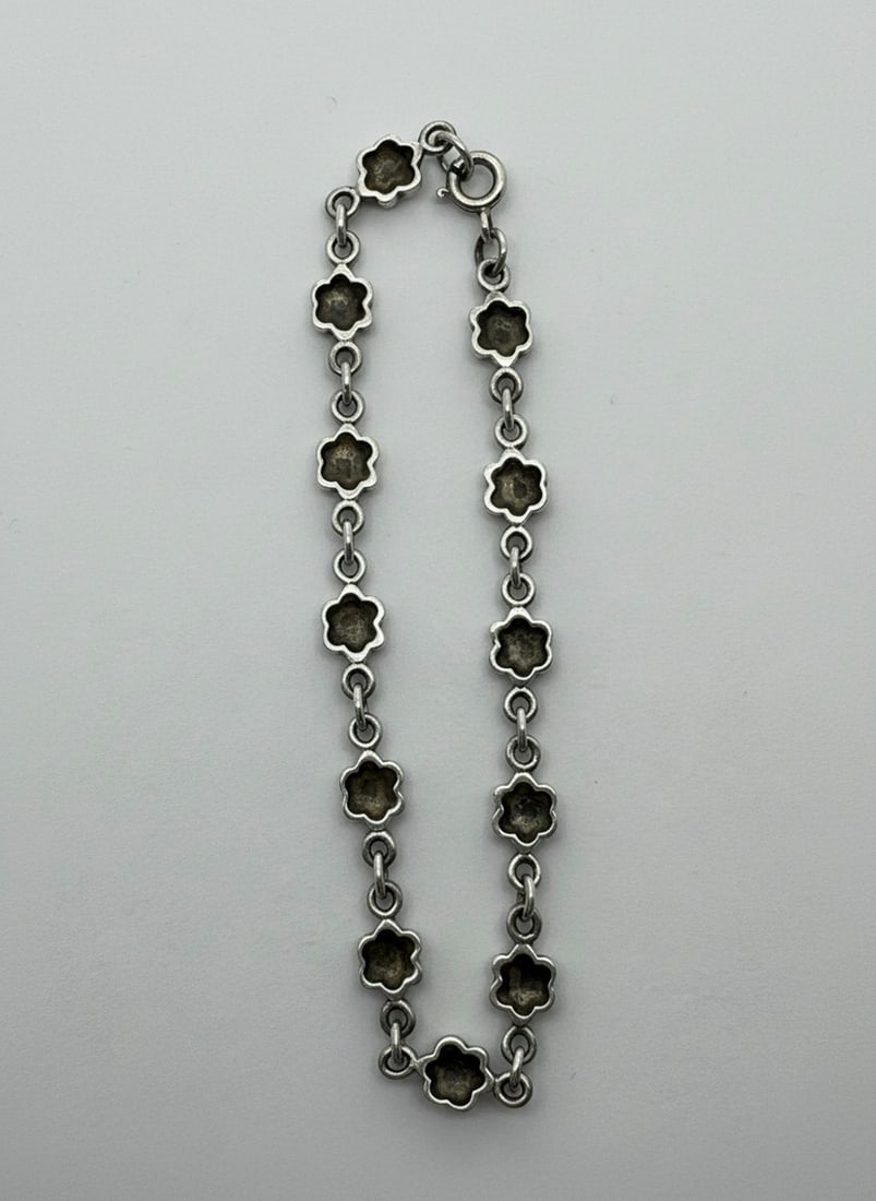 Sterling Silver Marcasite Flower Link Bracelet: This vintage-style bracelet features numerous sterling silver flower-shaped links, each detailed with marcasite stones in the center. The links are connected by small jump rings, forming a fluid