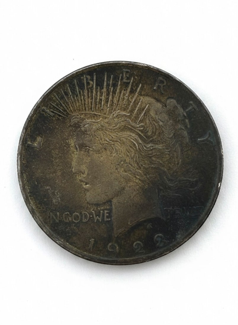 1923 US Silver Peace Dollar: This is a 1923 United States Silver Peace Dollar. The obverse features the left-facing profile of Lady Liberty, crowned with a radiate diadem. The reverse shows an eagle perched on a rock, holding an