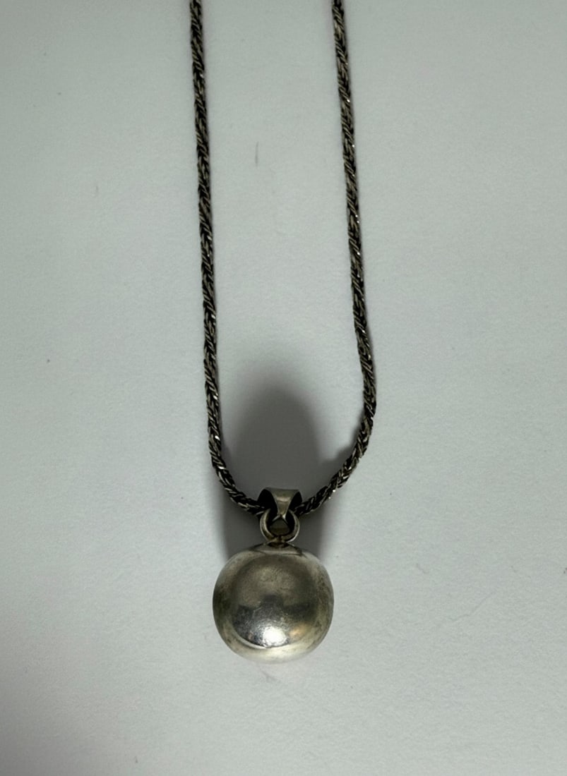 Sterling Silver Rope Chain Necklace with Spherical Pendant: A sterling silver rope chain necklace featuring a spherical pendant. The chain has a subtle rope-like texture and a lobster clasp. The pendant is a simple polished sphere. Jewelry Type: Necklace