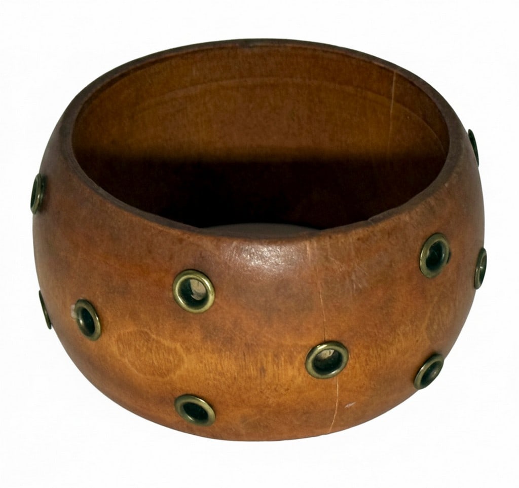 Wood and Brass Eyelet Bangle Bracelet: This contemporary bangle bracelet features a smooth, polished wood base adorned with a series of brass eyelets. The natural wood grain is visible, giving the piece an organic feel, complemented by