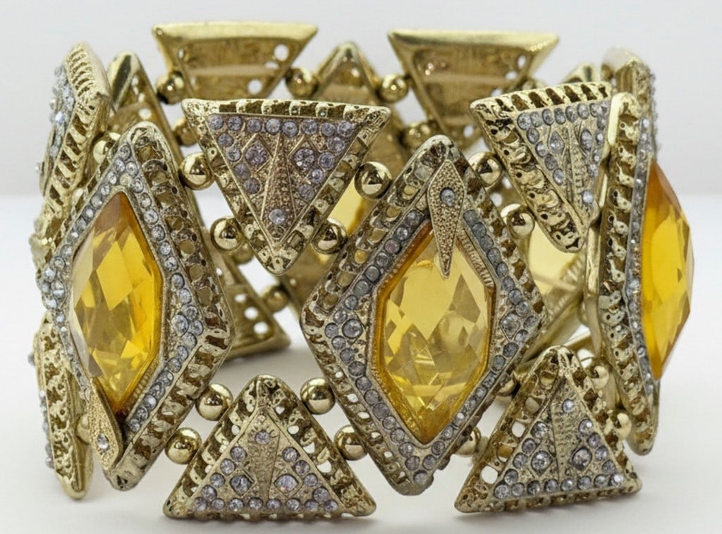 Gold-tone Costume Bracelet with Faceted Yellow Stones and Clear Accents: This chunky gold-tone costume bracelet features an ornate design with prominent faceted yellow stones, possibly glass or acrylic, each surrounded by clear rhinestone accents. The bracelet is composed