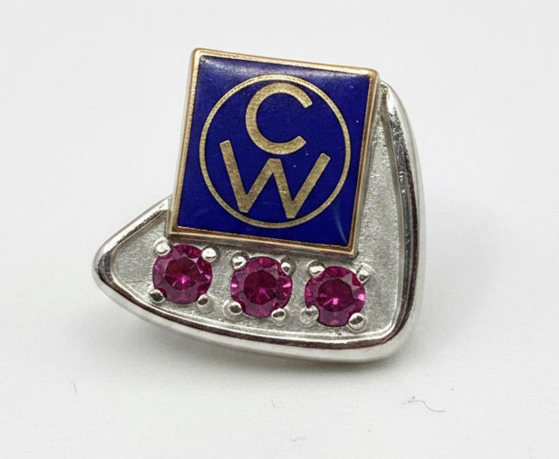 Vintage 10K Gold CW Enamel and Ruby Pin: A vintage 10K yellow gold pin, likely a fraternal or service pin, featuring a blue enamel squared top with "CW" initials in a circular motif, beneath which are three round-cut rubies. The pin has a cl