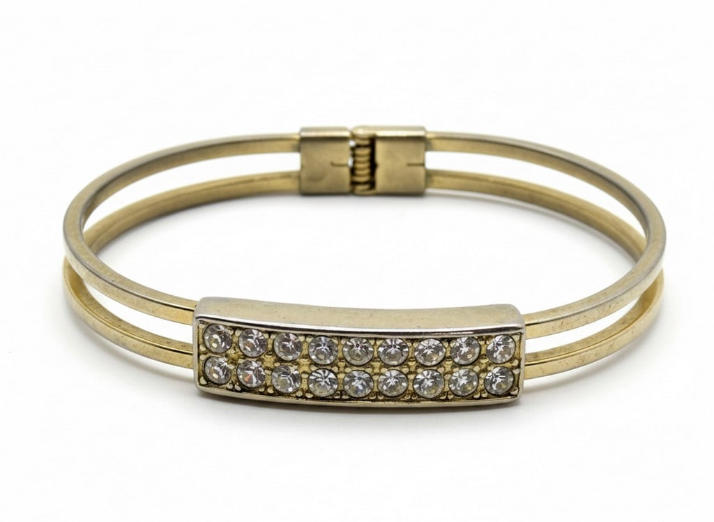 Gold-tone and Pave Crystal Bangle Bracelet: This vintage gold-tone bangle bracelet features a double-band design with a central rectangular plaque adorned with two rows of pave-set round crystals. The bracelet has a hinge closure for easy