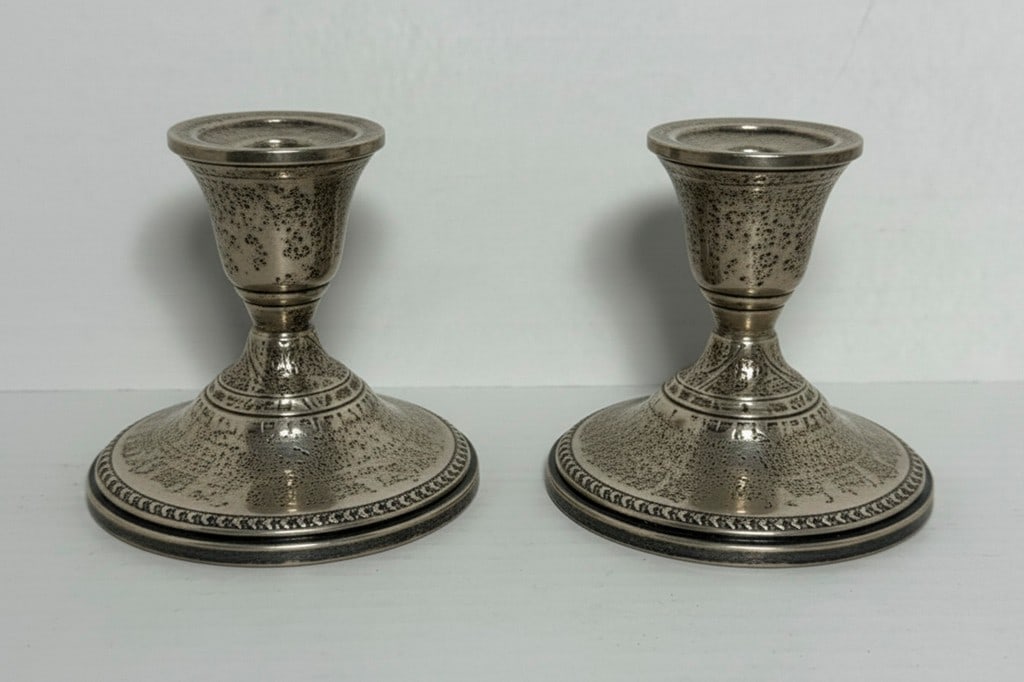 Pair of Sterling Silver Candlesticks, Reinforced with Cement: A pair of sterling silver candlesticks with a classic design. The bases are reinforced with cement for stability. Each candlestick features decorative banding and a polished finish. Marked "STERLING"