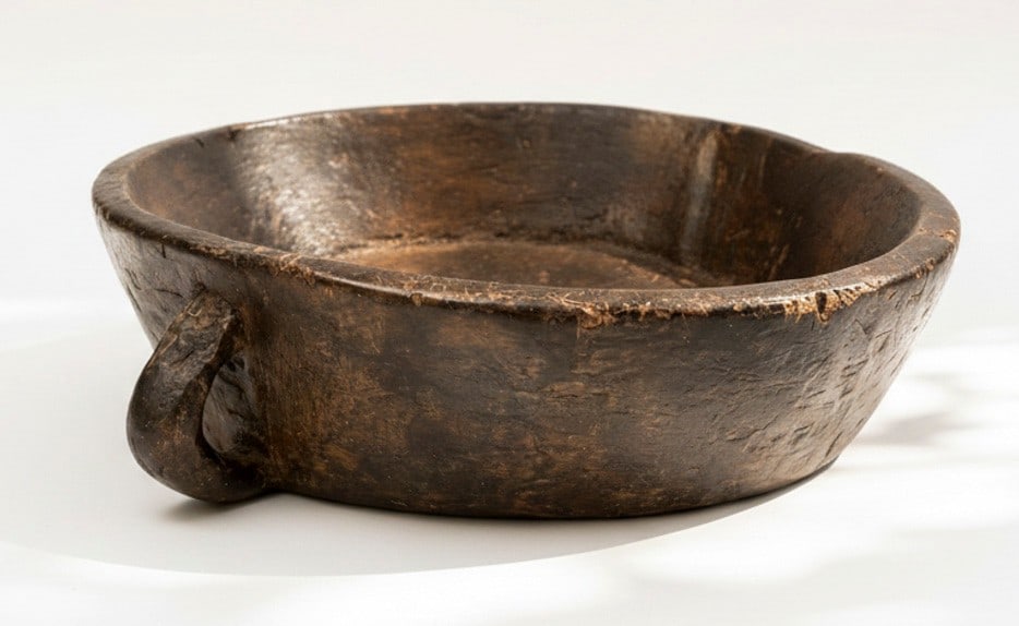 Large Salad Bowl Carved by Tribal Artisans in Northeast India - approximately 18 in. diameter: A large hand-hewn wooden bowl carved from a single block of hardwood, with a single integral loop handle. The vessel retains a deep, warm brown patina built up through age and use, the surface