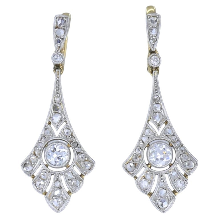 Antique 18k Gold Platinum Old Cut Diamond Drop Earrings, Early 20th Century: 18k yellow gold and platinum diamond drop earrings, circa 1910s to 1920s, designed with pierced platinum fronts over yellow gold construction. The earrings feature an elongated fan shaped drop with mi