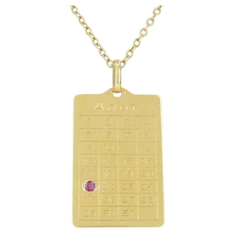 French 18k Gold Ruby 'August 21st' Calendar Pendant Chain Necklace: This late 20th century 18k yellow gold August calendar pendant necklace, designed as a rectangular calendar page for AoÃ»t, the French word for August. The pendant is engraved with a