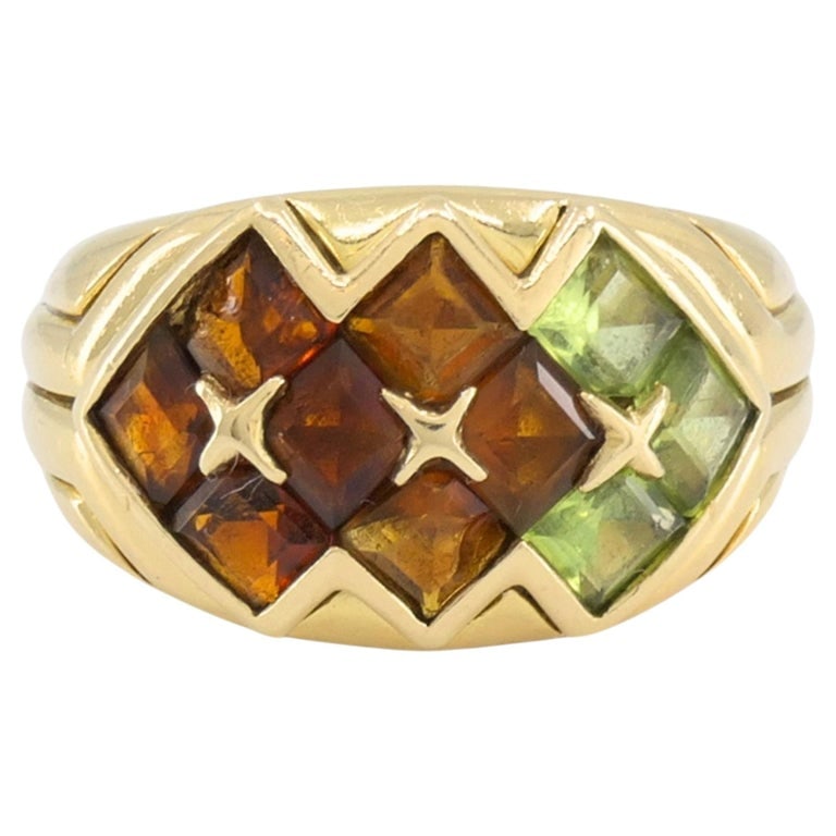 Bvlgari Bulgari Gemstone 18k Gold Ring circa 1990s: This Bulgari ring features a geometric arrangement of citrine, tourmaline, and peridot gemstones set in 18k yellow gold. The design is built around a series of lozenge-shaped stones placed closely
