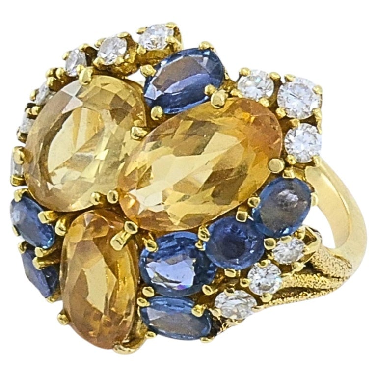 Vintage 14k Gold Imperial Topaz Blue Sapphire Diamond Cluster Cocktail Ring: This 14k gold ring is set with three oval imperial topaz, framed by blue sapphires and diamond accents in a domed cluster. The mix of warm yellow topaz and cool blue sapphires creates a natural color