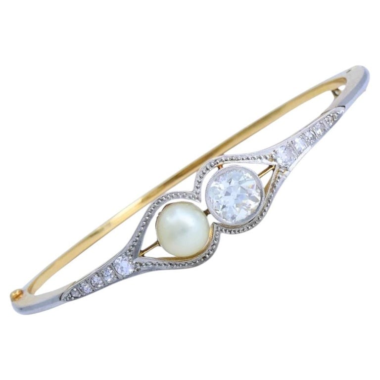 Edwardian Diamond Bracelet Pearl Gold Platinum Filigree Pattern: A refined Edwardian diamond bracelet crafted in 18k gold and platinum. The bracelet features a finely balanced design centered around an Old European cut diamond and a luminous pearl. The center diamo