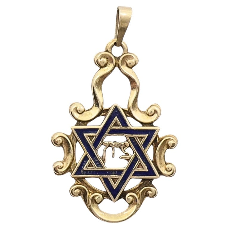 Vintage 14k Gold Blue Enamel Star of David Chai Pendant: A 14k gold Star of David pendant with blue enamel and a central Hebrew Chai. The gold frame has soft scroll details that give the piece a classic look without feeling too ornate. The enamel star adds