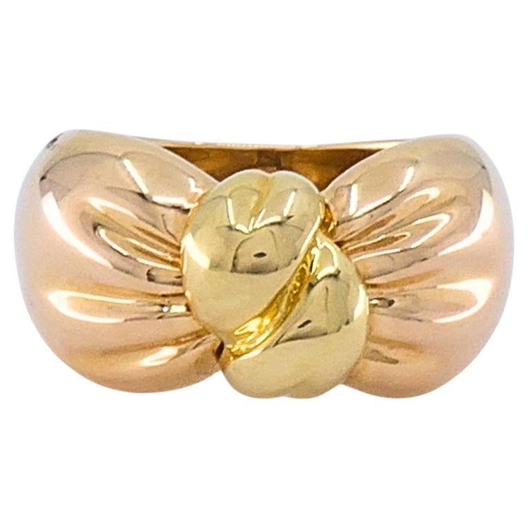 Van Cleef & Arpels 18k Two-Tone Gold Knot Ring: A Van Cleef & Arpels two-tone 18k gold knot ring, crafted in rose gold with a contrasting yellow gold center motif. The wide bombÃ©-style band tapers slightly at the shank, giving it a s