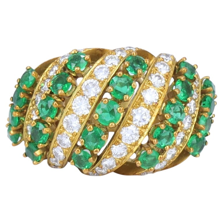 Vintage Asprey & Co. 18k Gold Emerald Diamond Cluster Cocktail Ring: This Asprey emerald and diamond ring is crafted in 18k yellow gold and reflects the structured, high jewelry design language of the late 20th century. The ring features a wide multi row crossover