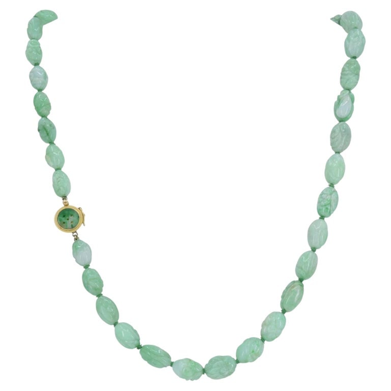 Vintage 14k Gold Apple Jade Carved Bead Necklace, Circa 1960s: This 14k gold apple jade carved bead necklace features a continuous strand of hand carved jade beads, each exhibiting a soft green tone with natural color variation. The beads are individually shaped 