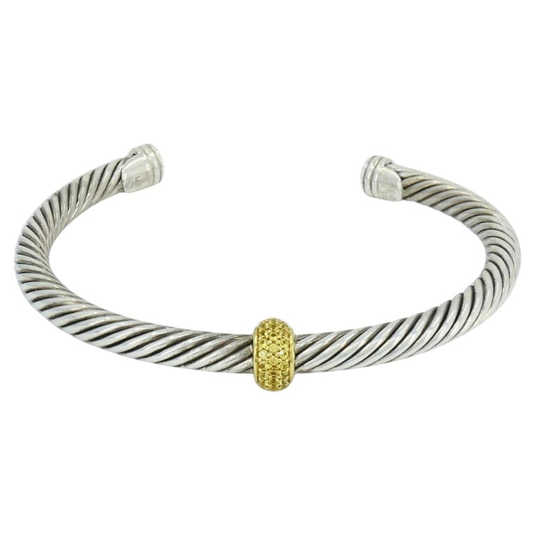 David Yurman 18k Gold Sterling Silver Sapphire Station Cable Cuff Bracelet: This David Yurman 5 mm cable bracelet is crafted in sterling silver and 18k yellow gold, incorporating the brandâ€™s well known twisted cable design with a central diamond station.