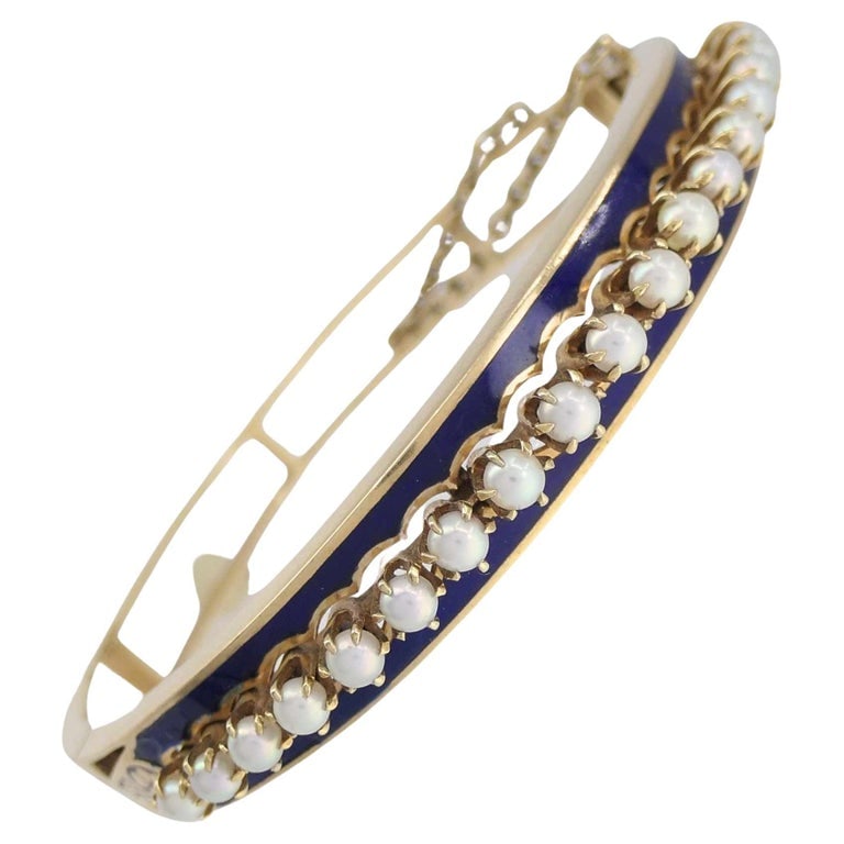 Victorian 14k Gold Pearl Enamel Hinge Bangle Bracelet: This bracelet is an antique Victorian bangle dating to the late 19th century, crafted in yellow gold with a hinged construction and safety chain typical of the period. The front features a row of