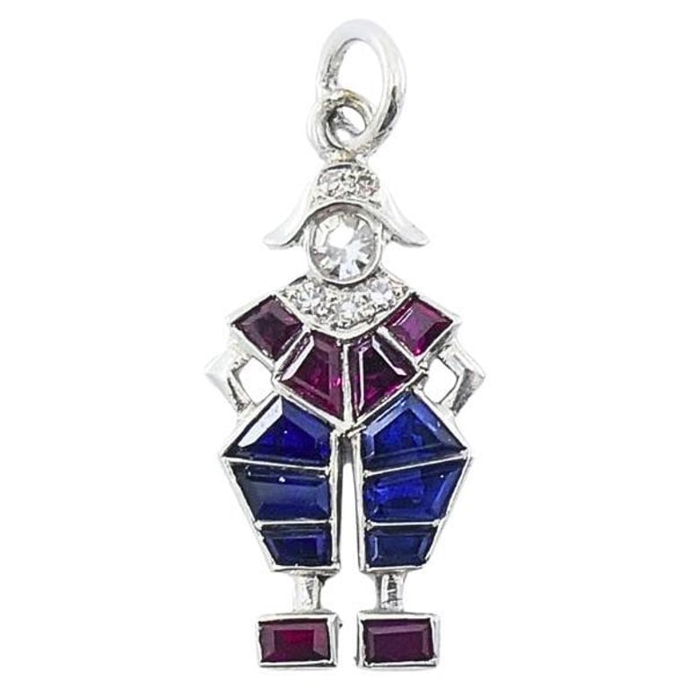 Antique Platinum Pierrot Charm Diamond & CalibrÃ©-Cut Gemstones: Art Deco clown charm set in platinum with red and blue gemstones and diamond accents in a whimsical geometric figural design. The charm is decorated with calibre cut gemstones in vivid red and blue,