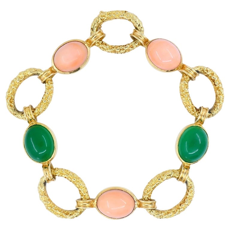 Vintage Van Cleef & Arpels 18k Gold Coral Chrysophrase Link Bracelet: This Van Cleef & Arpels bracelet from the 1990s is crafted in 18K yellow gold and set with alternating oval cabochons of pink coral and green chrysoprase. The stones are linked by textured gold