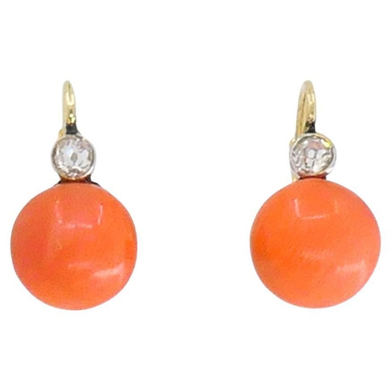 Vintage 14k Gold Coral Earrings Diamond Accent: A pair of cute vintage 14k gold coral earrings with a diamond accent. Each earring holds an oval coral bead with a natural orange tone. Above each coral bead sits a small diamond accent, adding a