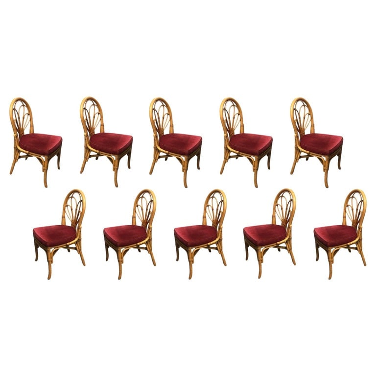 Restored Rattan Petal Fan Back Dining Chairs Set of 10: Discover the allure of vintage charm with our restored Paul Frankl-inspired rattan petal loop fan back dining chairs. Adorned in a dark red seat cushion, these chairs blend classic rattan intricacy