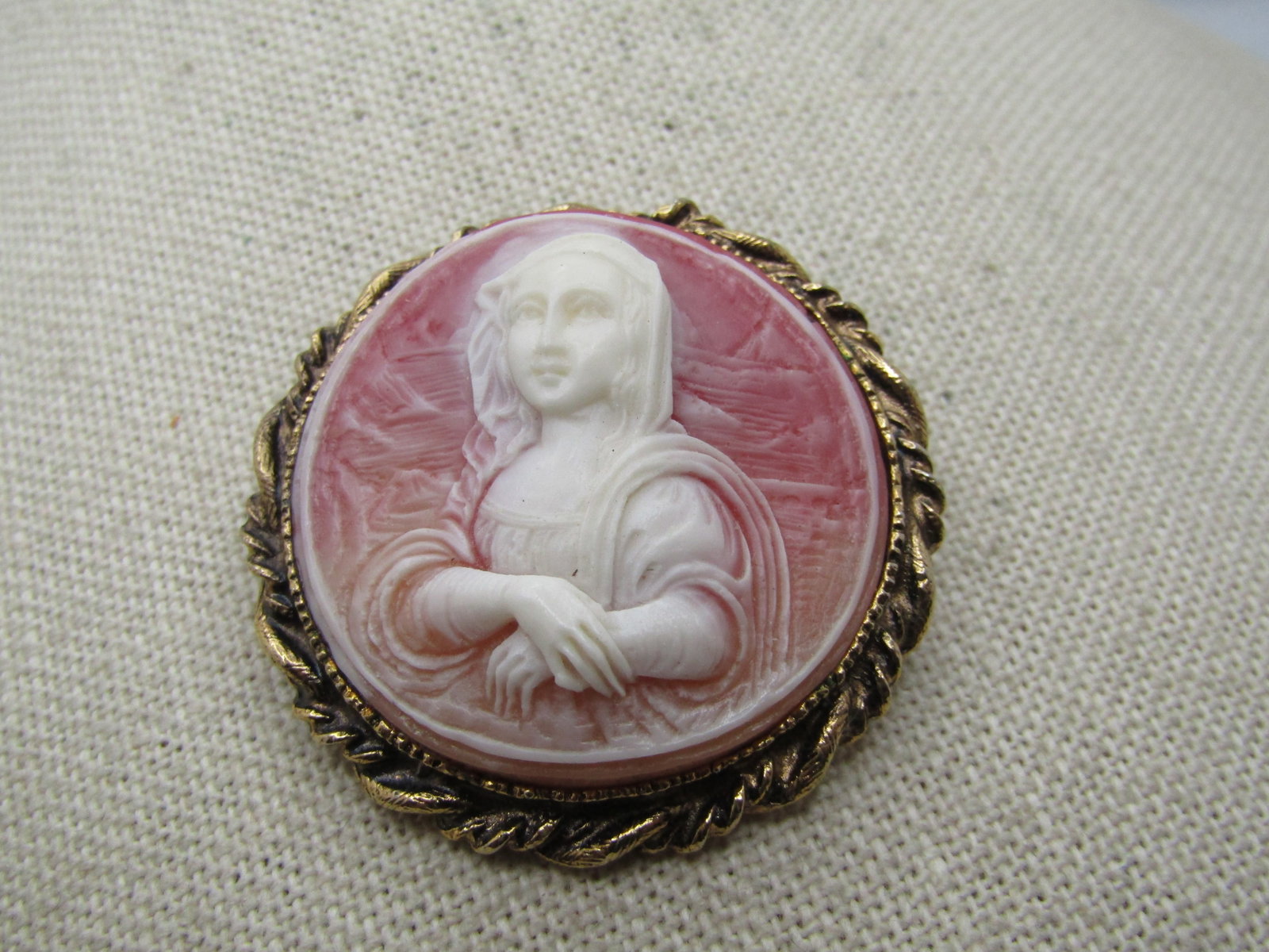 Vintage Pink Cameo Brooch, 1960's, Round: Title: Vintage Pink Cameo Brooch, 1960's, Round Description: Vintage Pink Cameo Brooch, 1960's, Round. This is appx. 1-5/8" round with gold tone twisted rope style frame. the cameo has the look of a