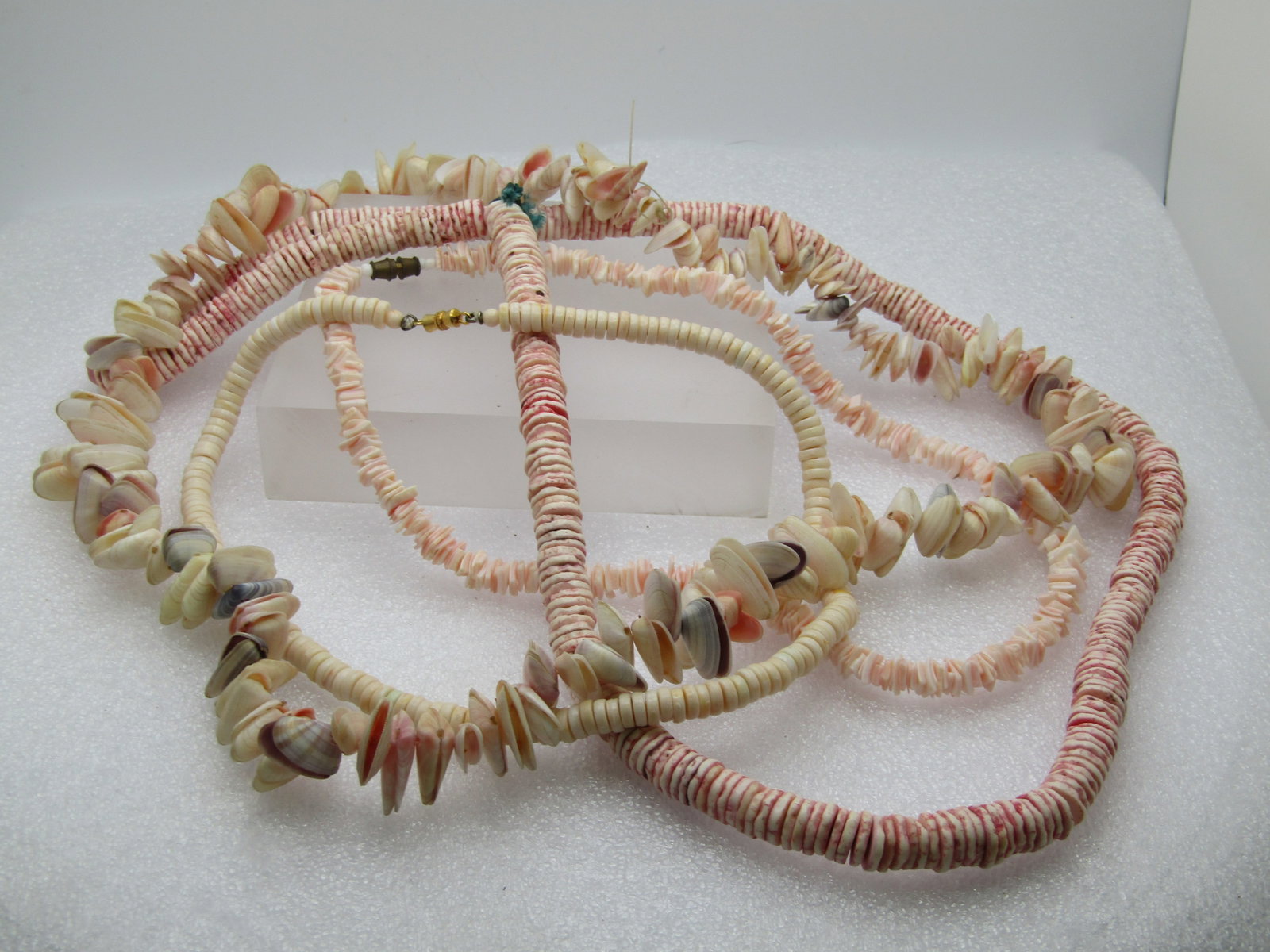 Vintage Four Shell Necklaces/Strands. The first is a 28" strand of pini/whited, likely dyed shell: Title: Vintage Four Shell Necklaces/Strands. The first is a 28" strand of pini/whited, likely dyed shell beads that are appx. 8.5mm wide. they are on a cord strand that is slipover to wear as a neckla