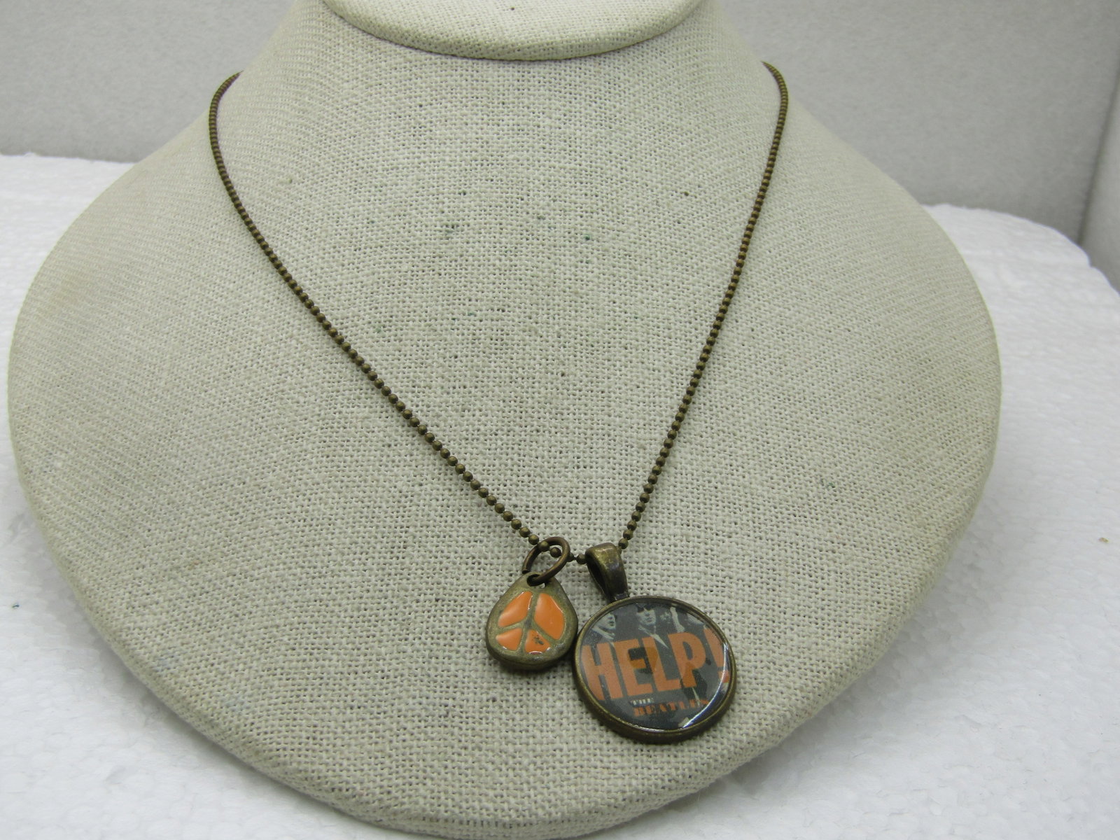 Vintage Peace Beatle's Help Necklace by Jasmine, New on Card: Title: Vintage Peace Beatle's Help Necklace by Jasmine, New on Card Description: Vintage Peace Beatle's Help Necklace 30" by Jasmine, New on Card. 30" beaded brassy gold tone chain. The pendant is a r