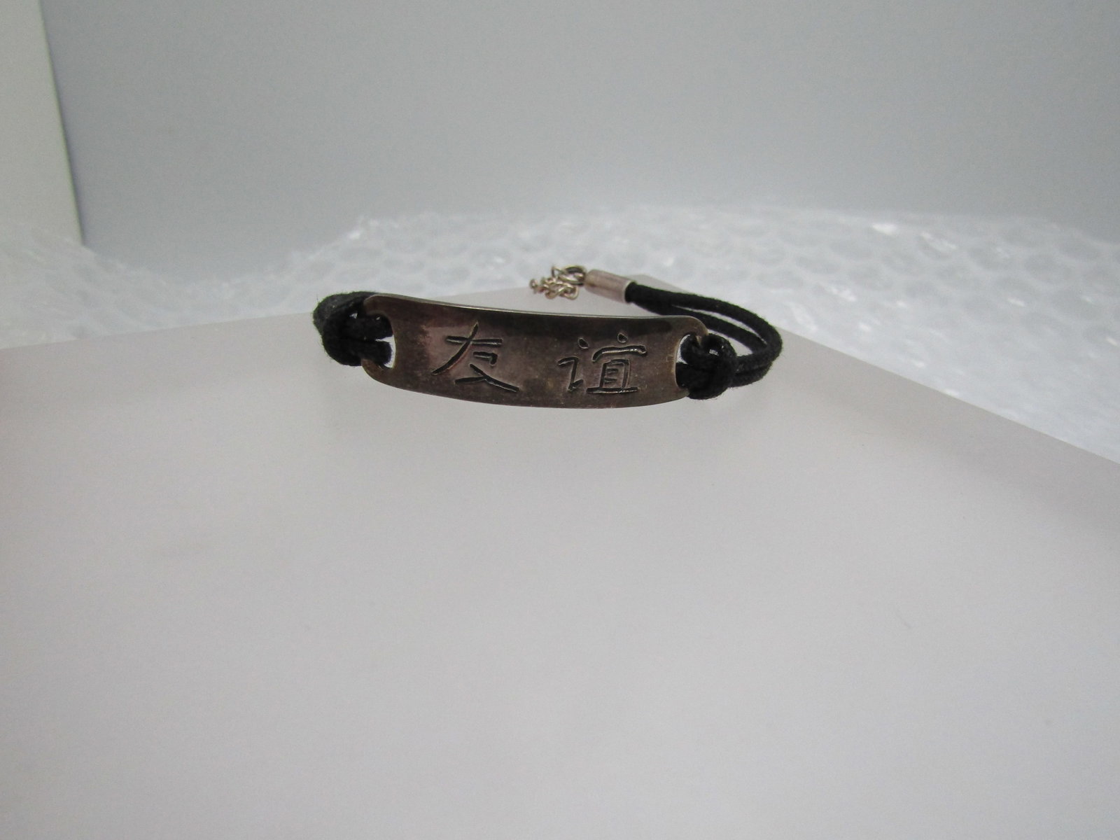 Vintage Sterling Asian Symbols Friend Bracelet, 7": Title: Vintage Sterling Asian Symbols Friend Bracelet, 7" Description: Vintage Sterling Asian Symbols Friend Bracelet, 7". Double strand black cord on each side of the sterling center piece. On the ba