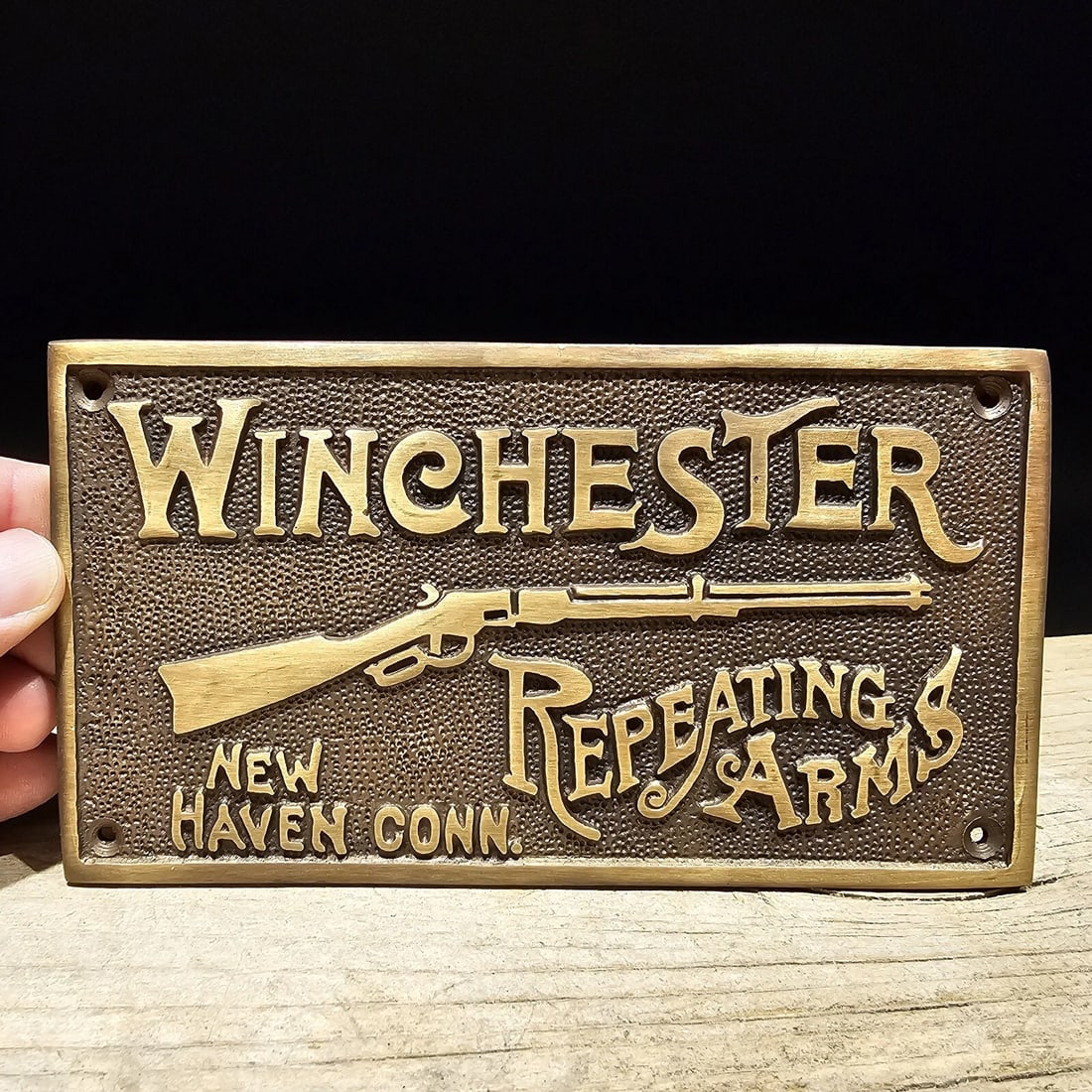 6 5/8" Brass Winchester Plaque Sign: 6 5/8" wide x 3 5/8" tall Wonderful reproduction Winchester firearms plaque. Good detail cast brass hand aged to look like an antique. Certainly hard to tell its age. Reserve: $40.00 Shipping: