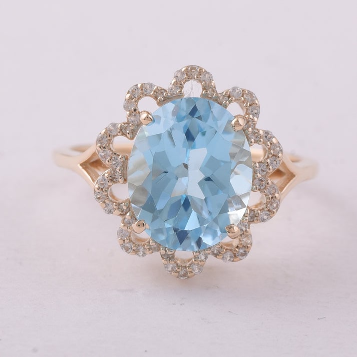4.72 Ct Oval Blue Topaz 9K Gold Ring: 4.72 Total Carat Blue Topaz 9K Gold Ring Specifications: Total Weight 3.004 g Center Gemstone Blue Topaz Gemstone Carat Weight 4.52 Carats Gemstone Measurements 11X9 mm Additional Gemstones White Sapp