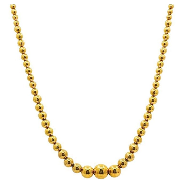 Aurafin 18k Yellow Gold Graduated Bead Necklace: Title: Aurafin 18k Yellow Gold Graduated Bead Necklace Description: This elegant Aurafin necklace is crafted in 18k yellow gold, featuring a classic graduated bead design that tapers gracefully from a