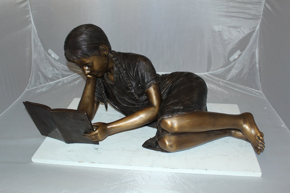 Girl laying reading a book Bronze Statue - Size: 36"L x 17"W x 18"H. - 5