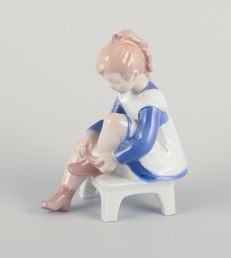 Bing & Grøndahll, Denmark. Porcelain figurine. Sitting girl tying a shoelace. Mid-20th century. - 2