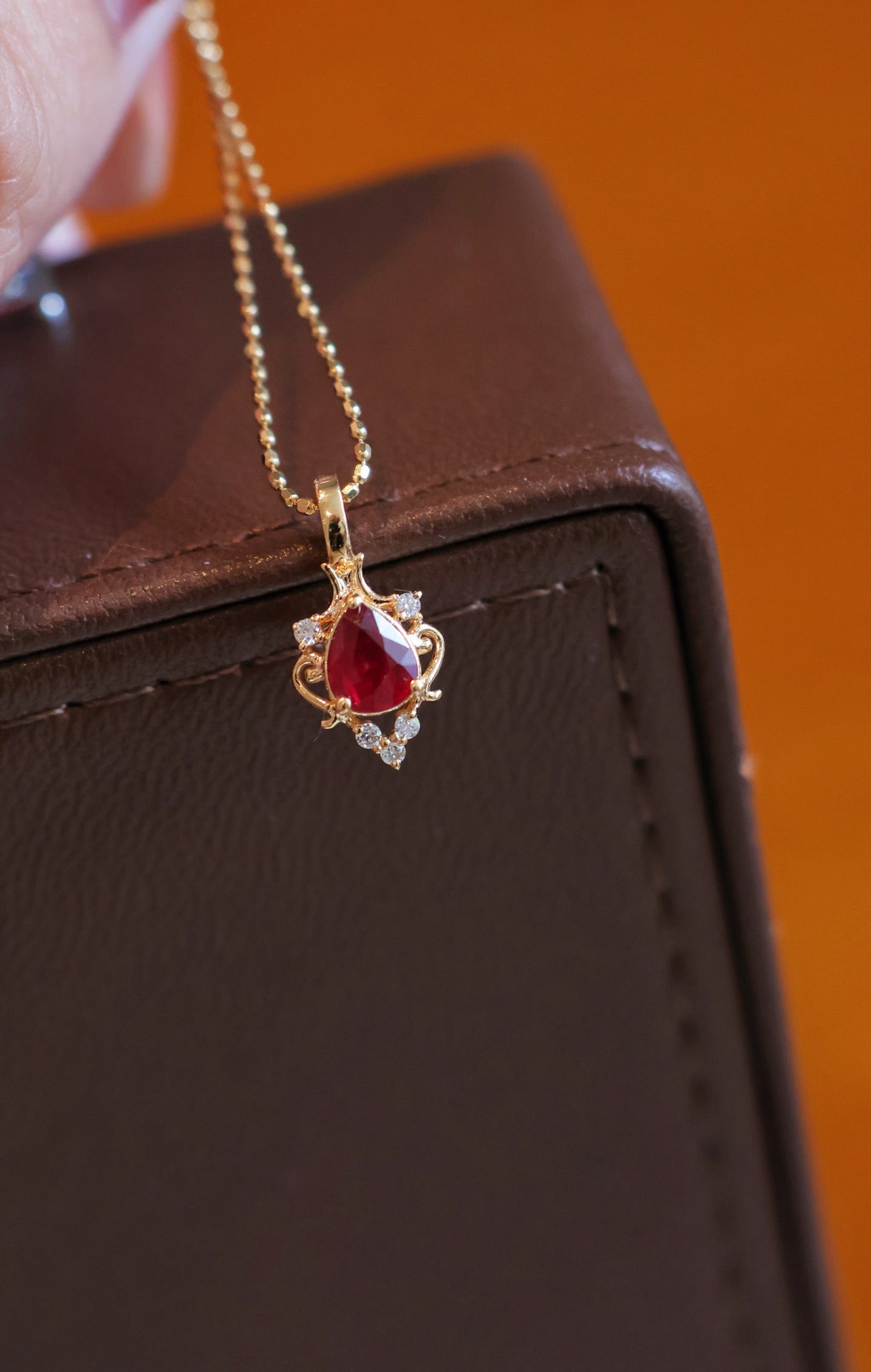 18K Gold Natural Ruby Diamond Pendant: Title: 18K Gold Natural Ruby Diamond Pendant Description: This pendant is meticulously crafted in 18K gold, featuring a vivid teardrop-shaped ruby as the centerpiece, surrounded by natural diamonds