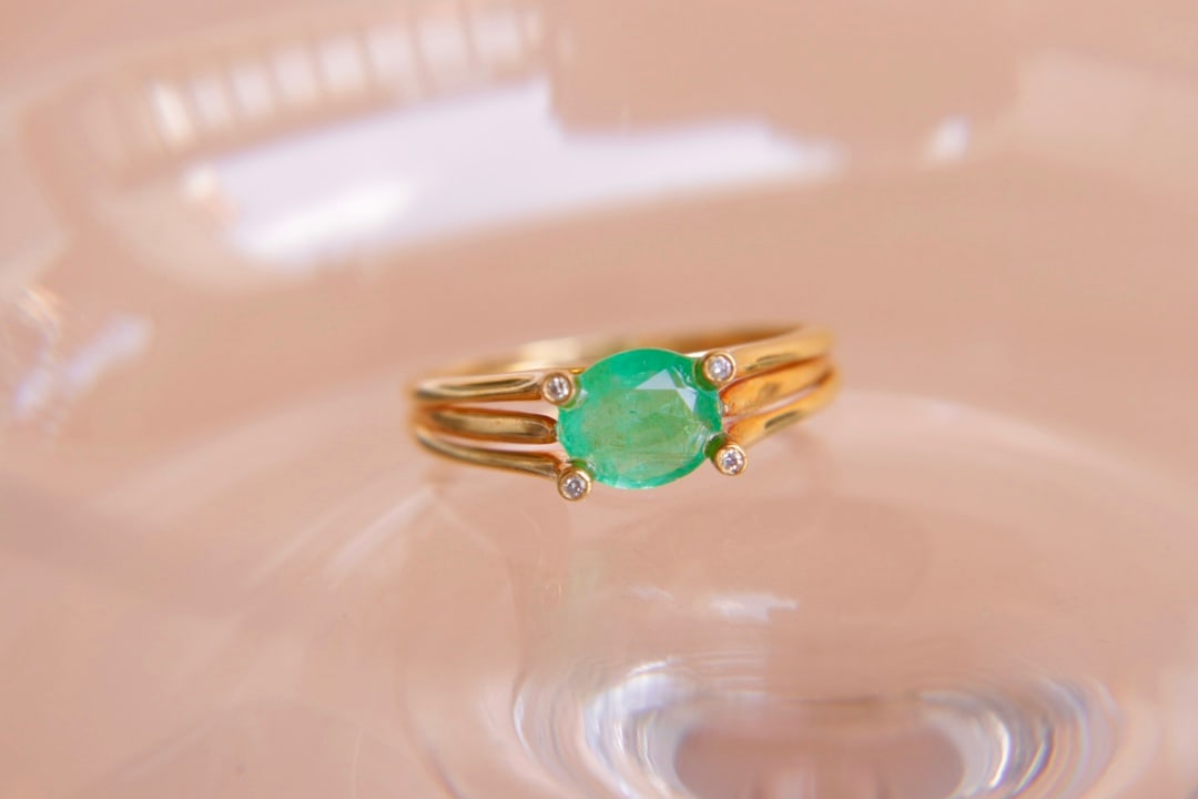 18K Gold Natural Emerald Diamond Ring: Title: 18K Gold Natural Emerald Diamond Ring Description: This 18K gold ring is set with a clean crystal emerald, showcasing its charming color. The exquisite design complements the brilliance of the