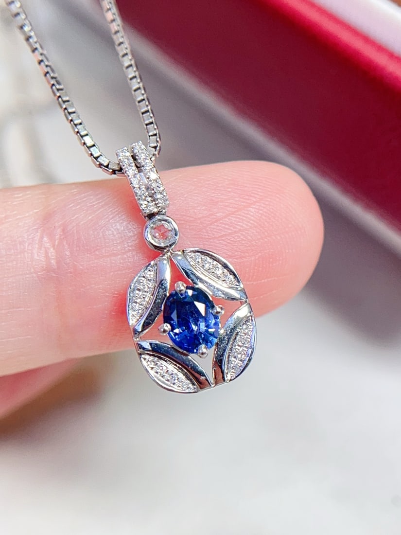 18K Gold Sapphire Pendant: Title: 18K Gold Sapphire Pendant Description: This pendant is crafted in 18K gold, featuring a sapphire with a unique cornflower hue. The main stone is approximately 0.45 carats, complemented by 28