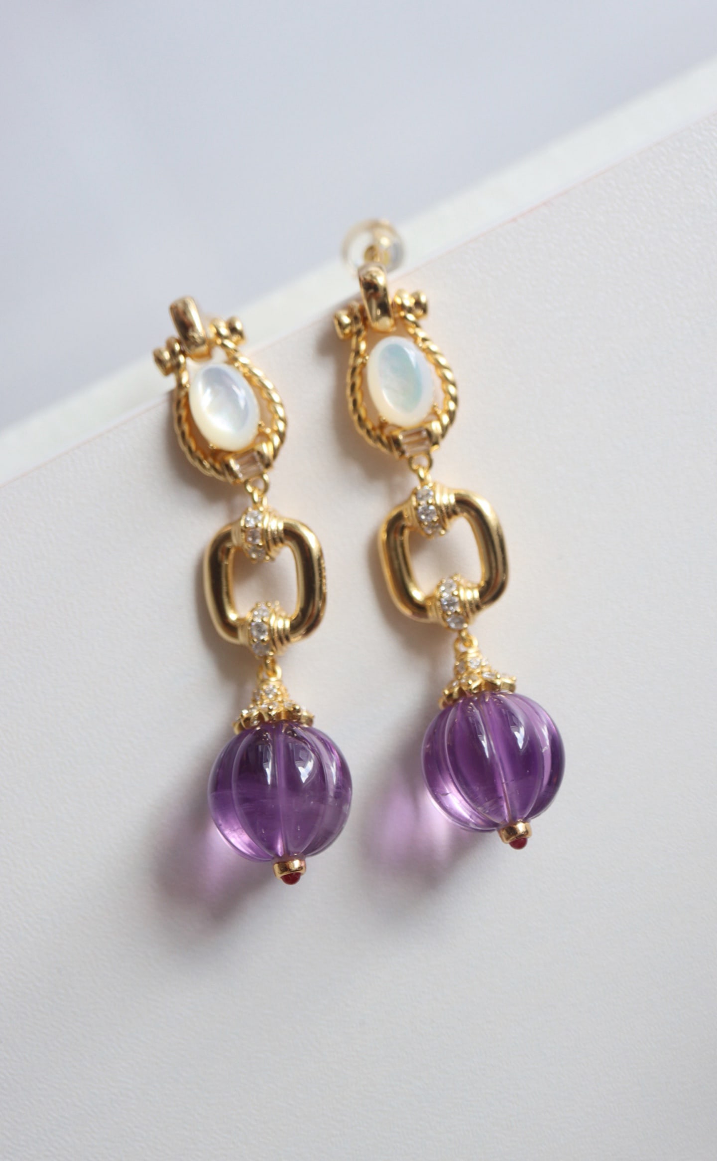 Natural Amethyst Earrings: Title: Natural Amethyst Earrings Description: These earrings feature natural amethyst as the main stone, complemented by white mother-of-pearl, exuding an elegant aura. The sterling silver is finely p